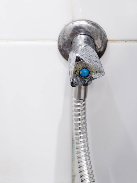 La vieille valve métallique avec la tache du système de tuyau de pulvérisation dans la salle de bain, avant le temps de remplacement, vue de face avec l'espace de copie. - Photo, image