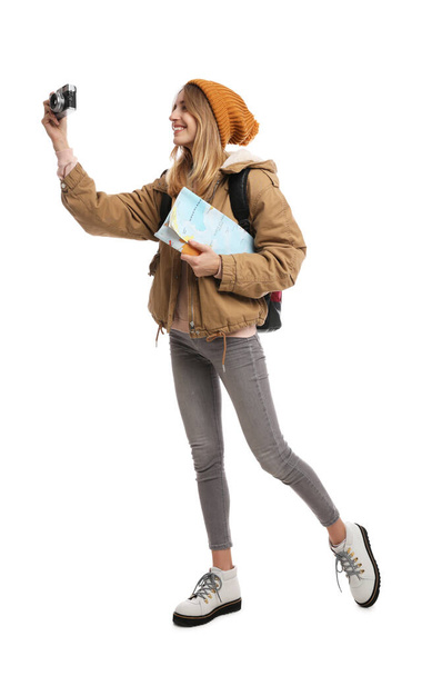 Vrouw met kaart en rugzak die foto 's neemt op een witte achtergrond. Winterreizen - Foto, afbeelding