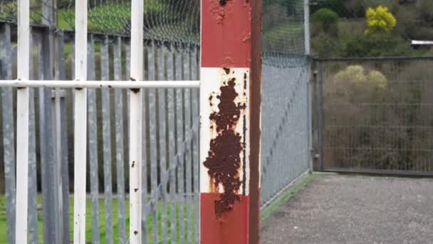 Rust on rusty old iron football goal at an abandoned asphalt outdoor sports ground and lattice fence in the forest - Footage, Video