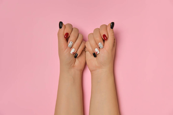 Detailní pohled na krásné ženské ruce s kreativními manikúrními nehty, bílým gelovým leskem, rty a XO designem, na růžovém pozadí, místo pro text - Fotografie, Obrázek