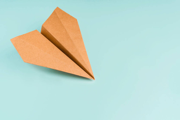 Paper airplane made of craft paper on a light blue background, space for text - Foto, afbeelding