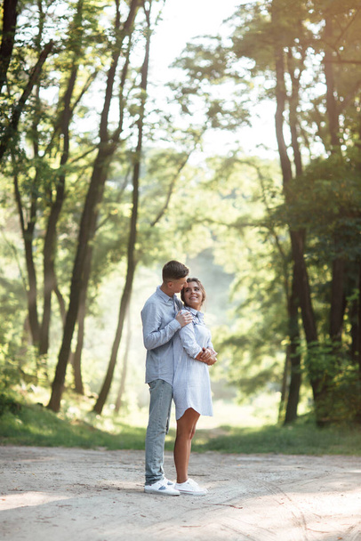 Outdoor shot of young happy couple in love on sunny day on nature. Man and woman hugging, sunlight in summer park. valentine's day. The concept holiday - Foto, imagen