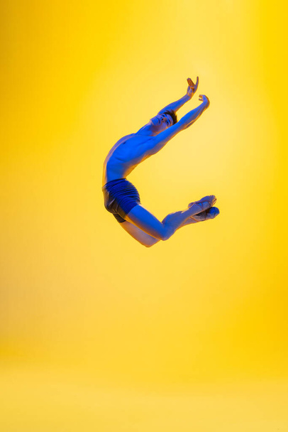 Young and graceful ballet dancer isolated on yellow studio background in neon light. Art, motion, action, flexibility, inspiration concept. - Foto, Bild