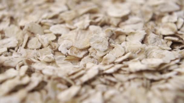 Los copos de cereales secos de avena caen en un montón en cámara lenta de cerca. Rotación - Metraje, vídeo