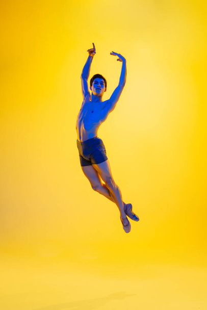 Young and graceful ballet dancer isolated on yellow studio background in neon light. Art, motion, action, flexibility, inspiration concept. - Fotografie, Obrázek