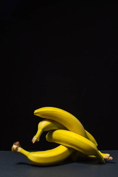 Plátanos sobre fondo negro. Comida saludable. Los plátanos se tejen juntos - Foto, imagen