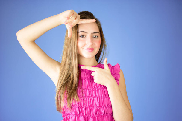 Schöne junge Mädchen Rahmen Geste über lila Hintergrund. - Foto, Bild