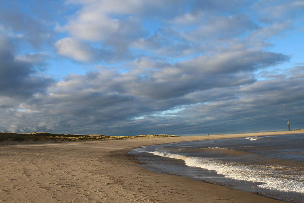 vue imprenable sur le paysage d'une vaste plage de sable avec un ciel bleu-rose reflété dans les piscines d'eau de mer alors que la marée océanique sort avec des bancs de sable herbeux fond dans Sea Palling Norfolk East Anglia uk avec le soleil de fin d'été à travers des nuages gris orageux - Photo, image