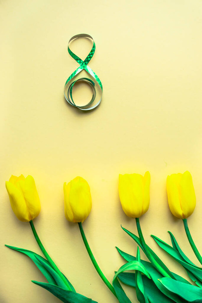 Aurinkoinen kukka järjestely. Keltaiset tuoreet tulppaanit, joiden keskellä on numero 8 keltaisella paperilla. Kansainvälisen naistenpäivän tervehdyskortti 8. maaliskuuta. Valikoiva keskittyminen. Litteä pano. Kopioi tila. - Valokuva, kuva