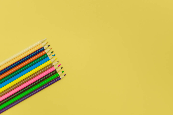 colored pencils on a yellow background - Foto, imagen