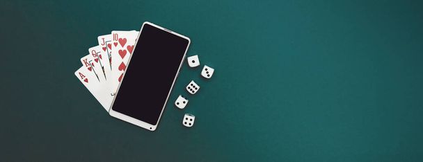 игральные карты в покер кости и телефон на зеленой синей ткани панорама - Фото, изображение