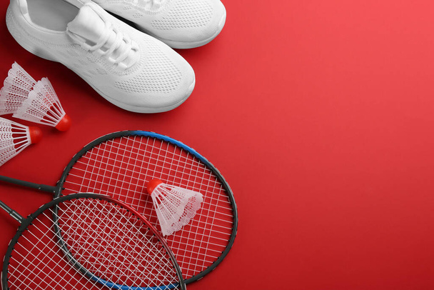 Badminton rackets, shuttlecocks and shoes on red background, flat lay. Space for text - Foto, Imagem