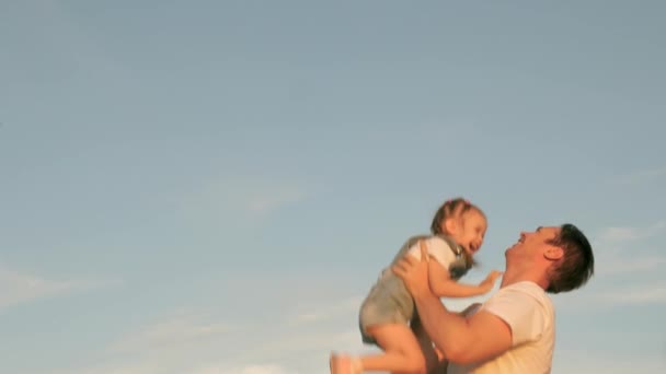 Dad tosses his happy daughter into blue sky. Father and healthy child play together, laugh and hug. carefree kid flies into sky. child is in the arms of parents. Dads day off. Happy family concept - Footage, Video