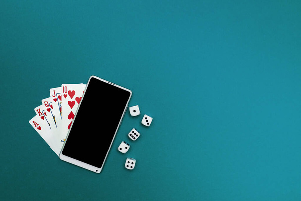 игральные карты в покер кости и телефон на зеленой синей ткани - Фото, изображение