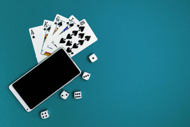 игральные карты в покер кости и телефон на зеленой синей ткани - Фото, изображение