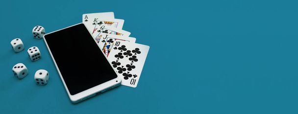 игральные карты в покер кости и телефон на зеленой синей ткани панорама - Фото, изображение