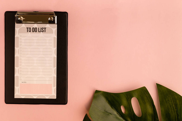 Mockup with clipboard and monstera leaf on pink background. Flat lay, top view, copy space. - Photo, Image