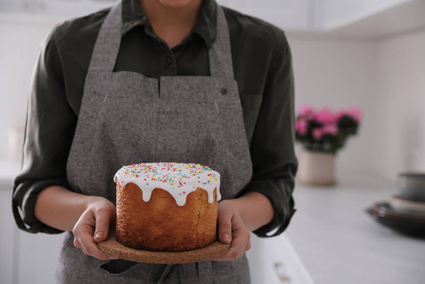Young woman with traditional Easter cake in kitchen, closeup. Space for text - Foto, Bild