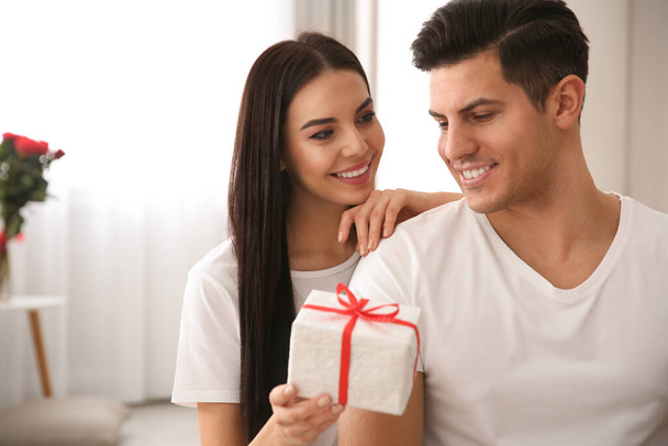 Lovely couple with gift box at home. Valentine's day celebration - Φωτογραφία, εικόνα