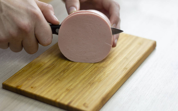 Slice the sausage.Men's hands are slicing sausage. - Photo, Image
