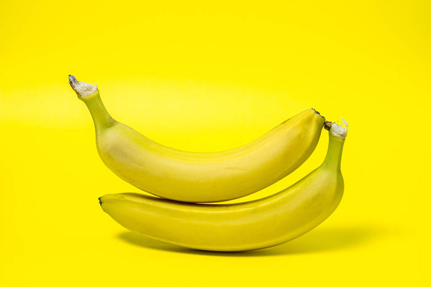 Bananen op een gele achtergrond. Verse gele bananen. Bananen zitten boven op elkaar. Exotische vruchten - Foto, afbeelding