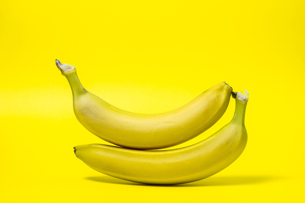 黄色の背景にバナナ。新鮮な黄色のバナナ。バナナが重なっている。エキゾチックな果物 - 写真・画像