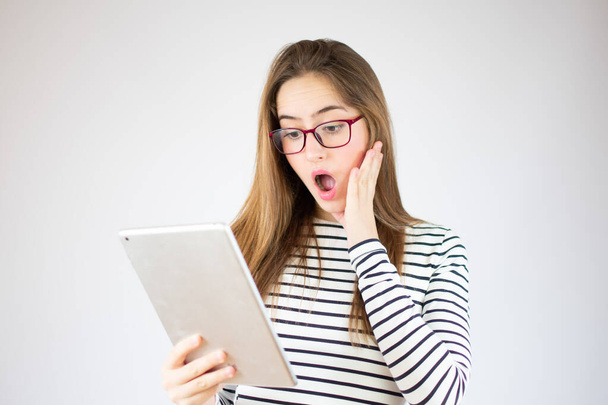 Surprised young girl using digital tablet over white background, copy space - Фото, изображение