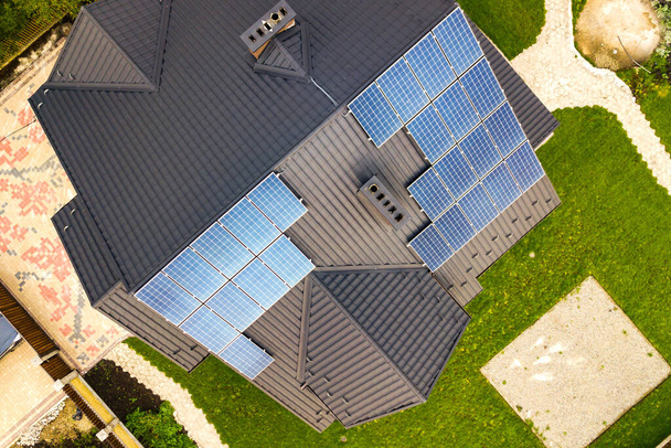 Вид с воздуха на сельский частный дом с солнечными фотоэлектрическими панелями для производства чистой электроэнергии на крыше. Автономная концепция дома. - Фото, изображение
