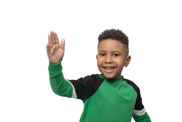 Натисніть емоційний портрет маленького темношкірого африканського хлопчика у жовтій сорочці на білому фоні у студії - Фото, зображення