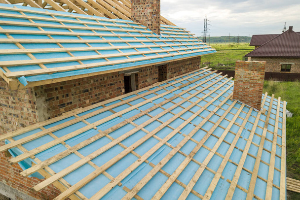 Вид с воздуха на кирпичный дом с деревянным каркасом крыши в стадии строительства. - Фото, изображение