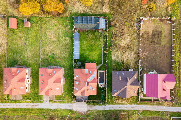 Αεροφωτογραφία αγροτικού ιδιωτικού σπιτιού με ηλιακούς φωτοβολταϊκούς συλλέκτες για την παραγωγή καθαρής ηλεκτρικής ενέργειας στην οροφή. Αυτόνομη κατοικία σε κατοικημένη περιοχή έννοια. - Φωτογραφία, εικόνα