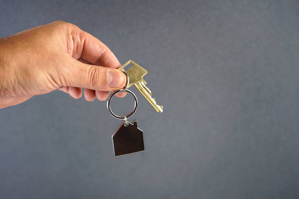 Overhandigen van sleutel met huisvorm zwarte sleutelhanger.  - Foto, afbeelding