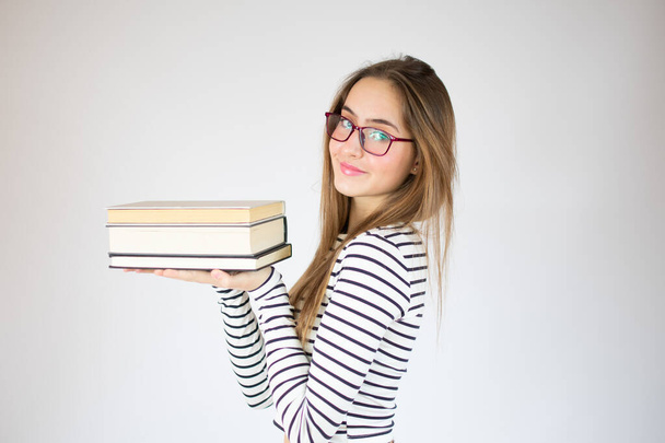 Junge schöne Mädchen mit Brille, die Bücher über weißem Hintergrund hält. - Foto, Bild