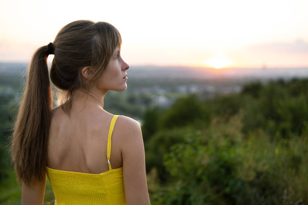 Молода жінка на відкритому повітрі насолоджується видом на захід сонця
. - Фото, зображення