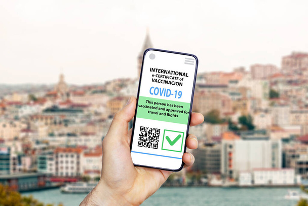 旅行者のためのコロナウイルス予防接種証明書またはワクチンパスポートをコンセプト。国際旅行のためのスマートフォンのモバイルアプリでCOVID-19免疫電子パスポート。歴史的建造物の背景 - 写真・画像