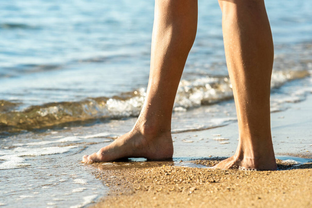 Крупный план женских ног, идущих босиком по песку, оставляющих следы на золотом пляже. Концепция отпуска, путешествий и свободы. Люди отдыхают летом. - Фото, изображение