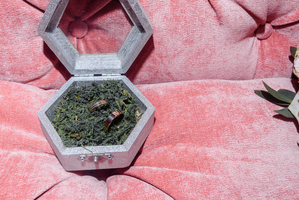 witgouden trouwringen in een doos en een bruidsboeket van delicate rozen en groen - Foto, afbeelding
