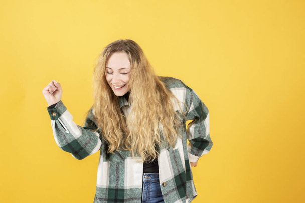 pretty blonde caucasian woman, dancing yellow background,copy space - Foto, afbeelding