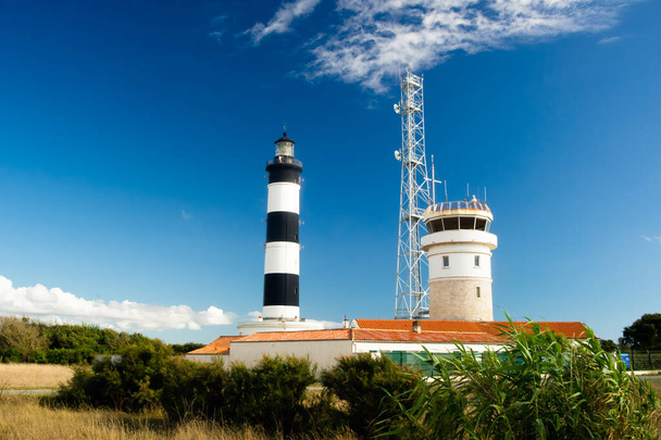 シャシロン島の青い空と夏の雲とテラコッタの屋根の上の灯台、オロン島、フランス - 写真・画像