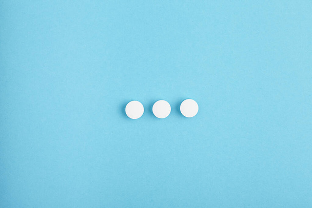 Closeup of white pills on a blue background. Heap of pills - medical background - Foto, imagen