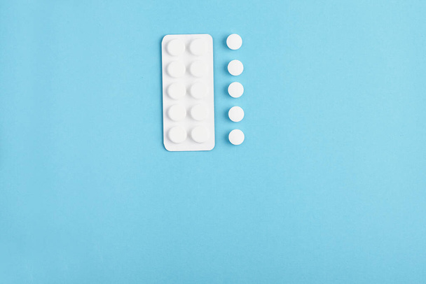 Szekrény fehér tabletták és buborékcsomagolás kék alapon. Egy halom tabletta - orvosi háttér - Fotó, kép