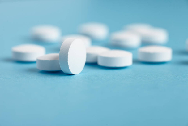 Closeup of white pills on a blue background. Heap of pills - medical background - Φωτογραφία, εικόνα