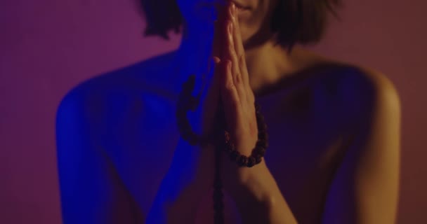 Neon ışıkta dua eden çıplak kız. Neon ışığıyla aydınlanan Çıplak Kız Yüzü Yok. Giysileri olmayan seksi bir kadın elinde bir tespih tutuyor ve dua okuyor. İnanç ve Ruhsal - Video, Çekim