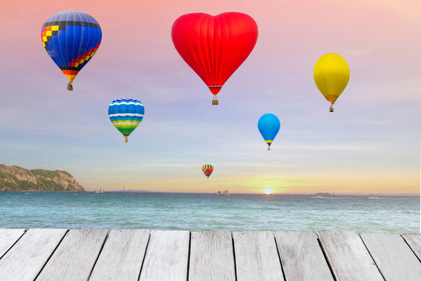 Повітряні кульки літають на морі під час заходу сонця або сходу сонця, а дерев'яна дошка з копіювальним простором. Це концептуальна картина
. - Фото, зображення