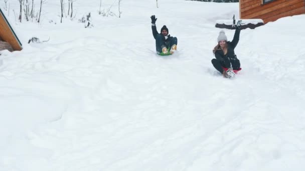 Зимние развлечения на открытом воздухе. Молодой человек и женщина скользящие по снегу - Кадры, видео