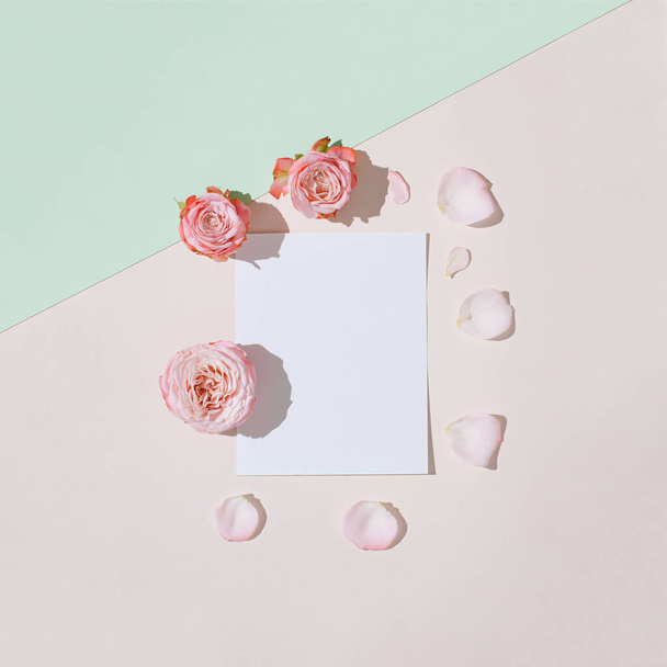Composition créative réalisée avec des fleurs roses et note de carte de papier sur le fond vert tendre et beige. Pose minimale d'appartement d'été. - Photo, image