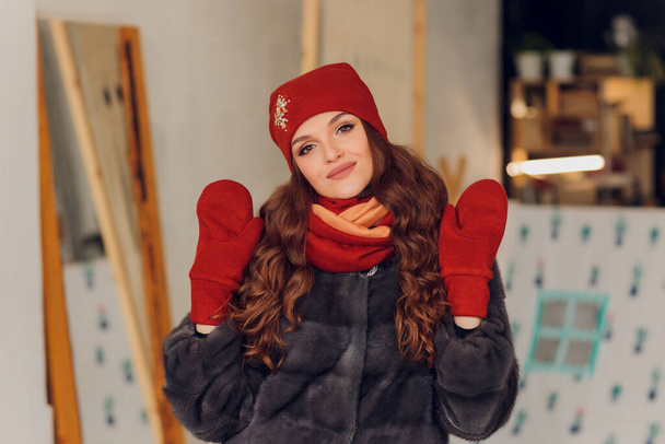 happy beautiful woman looking sideways in excitement. girl wearing knitted warm hat and mittens. - Fotó, kép