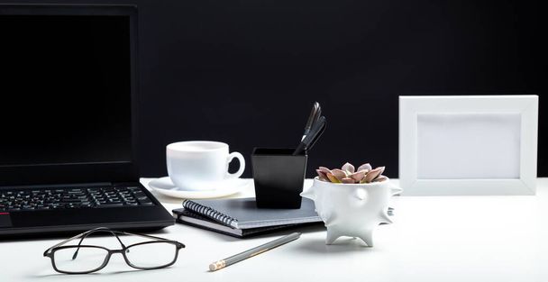 White table with laptop. Office homeworkspace for work or study in Office interior. Black laptop with blank display layout template on black background. Long web banner - Photo, Image