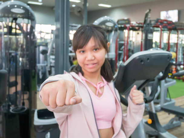 Asiatisch teenager mädchen acting punch sie smile und entspannen nach übung im die fitnessstudio. - Foto, Bild