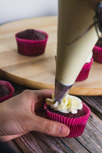 Süteményes cukrász süteményes zsákkal díszített muffinok. - Fotó, kép